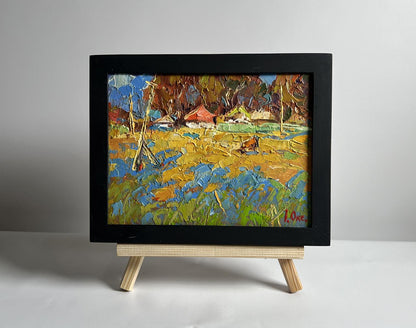 Oil painting by Oksana Ivanyuk: vibrant cow in field near village, framed