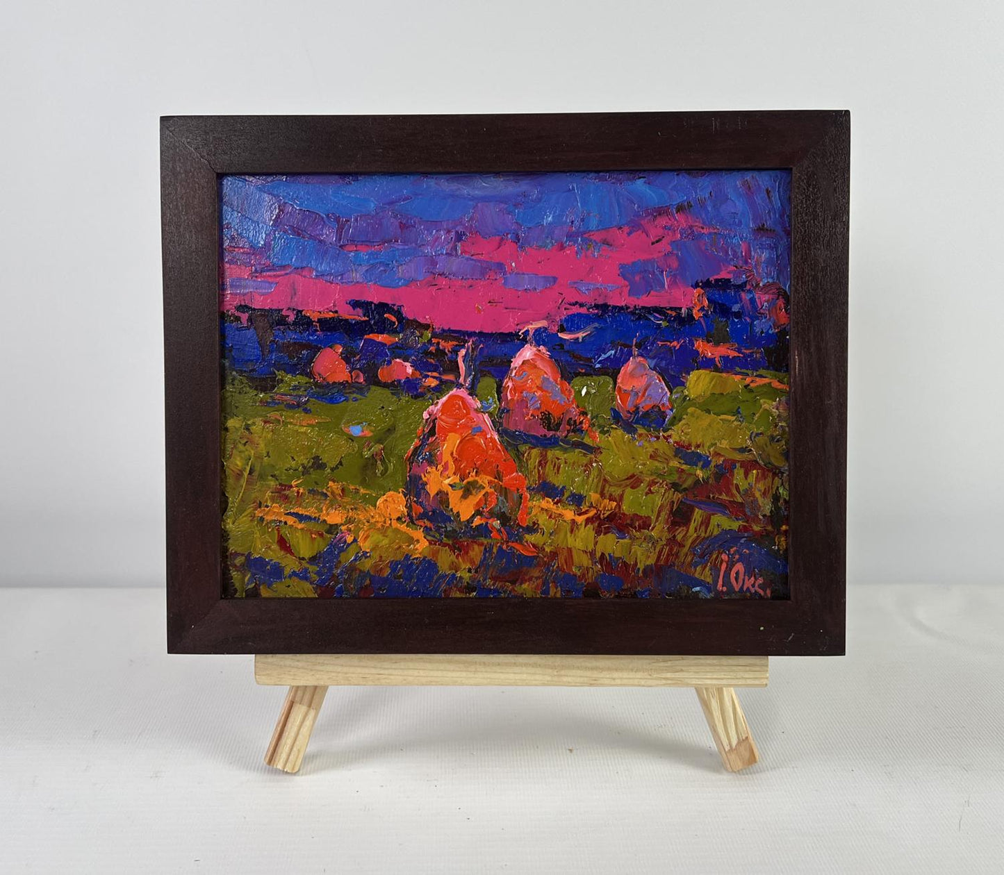 Vibrant impressionist oil painting Evening silence in the field by Oksana Ivanyuk, hay bales under pink blue sky in dark wooden frame