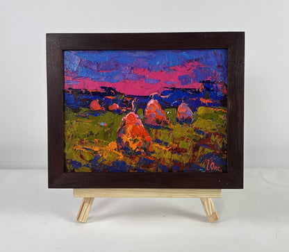 Vibrant impressionist oil painting Evening silence in the field by Oksana Ivanyuk, hay bales under pink blue sky in dark wooden frame