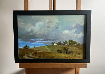 Framed oil painting of rolling countryside under grey clouds by Yuriy Suprunchuk