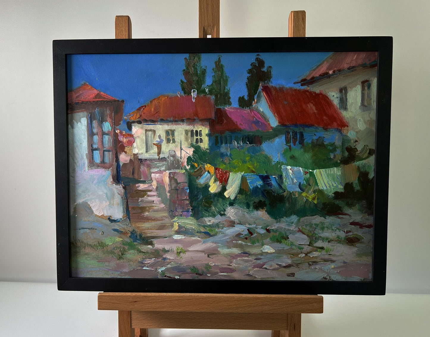 Oil painting of village life by Yuriy Suprunchuk with red roofs