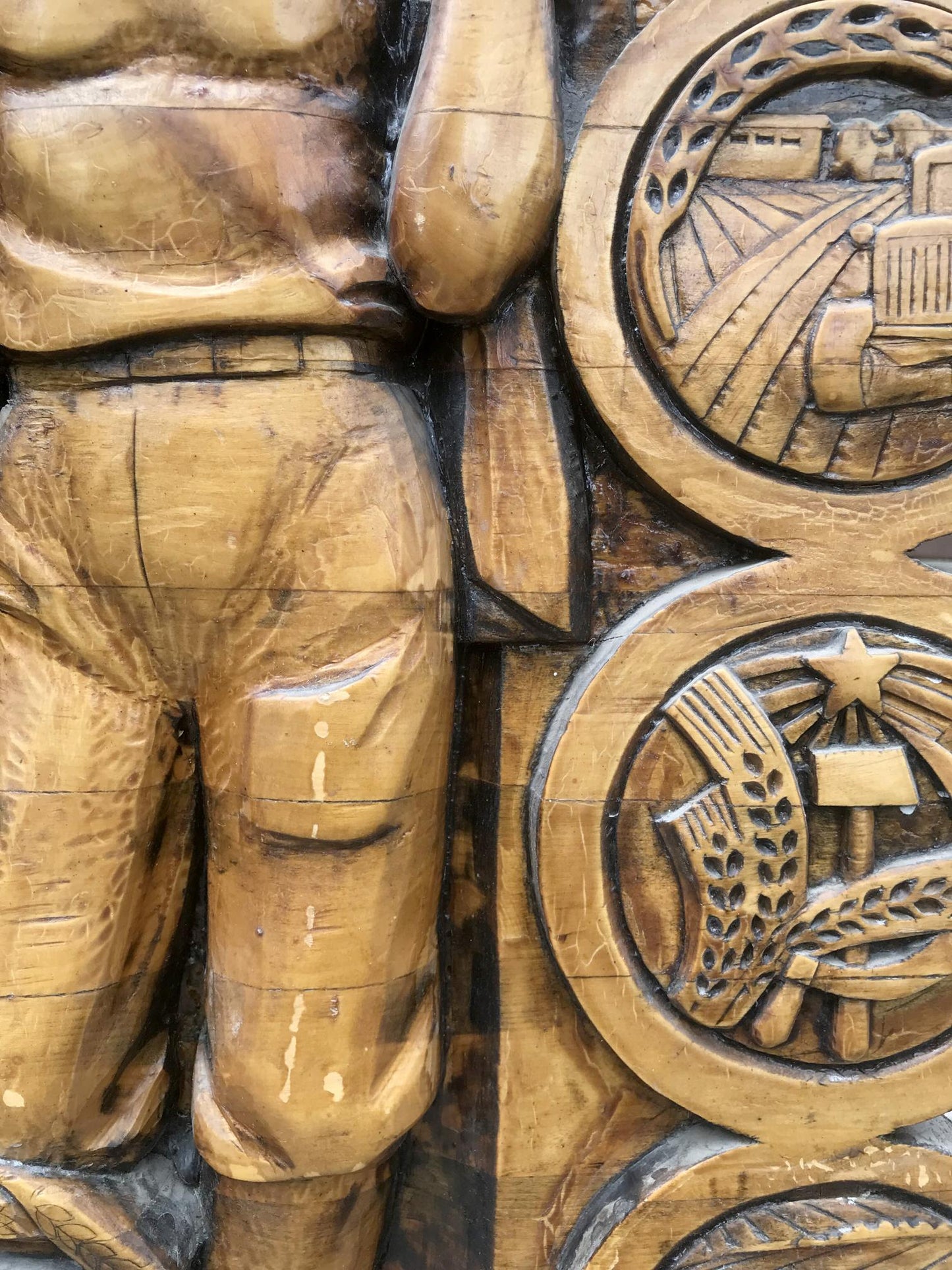 Carved wooden relief of communist labor brigade worker and farm symbols in warm tones
