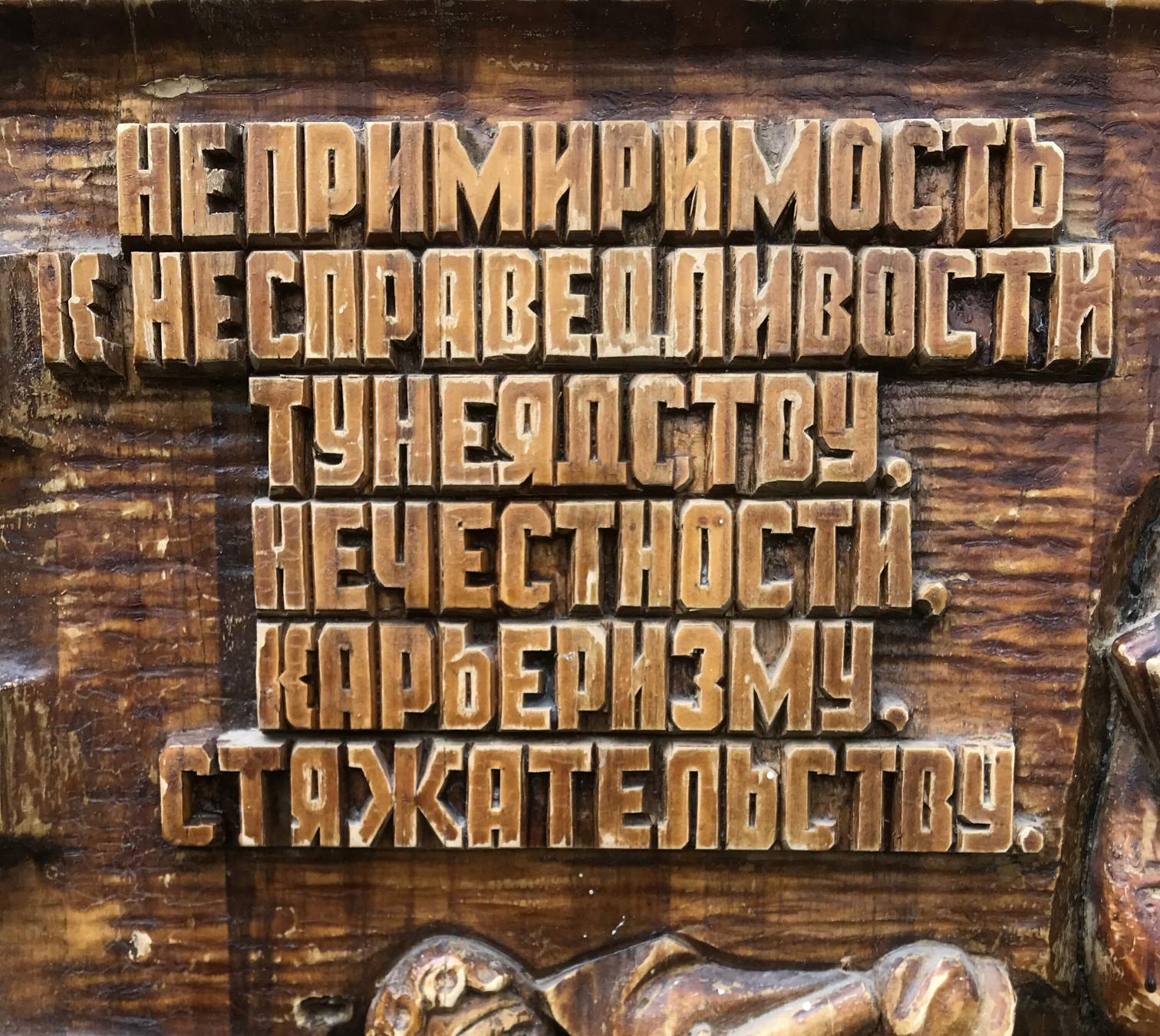 Carved wooden plaque with raised Cyrillic text on social realism theme