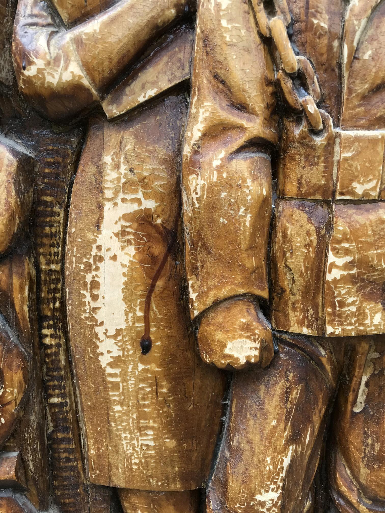 Weathered golden-brown wooden carving of intransigent social realist figure