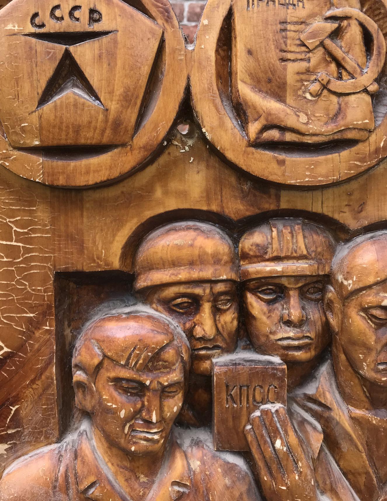 Carved wooden relief of Soviet-era symbols in warm brown tones
