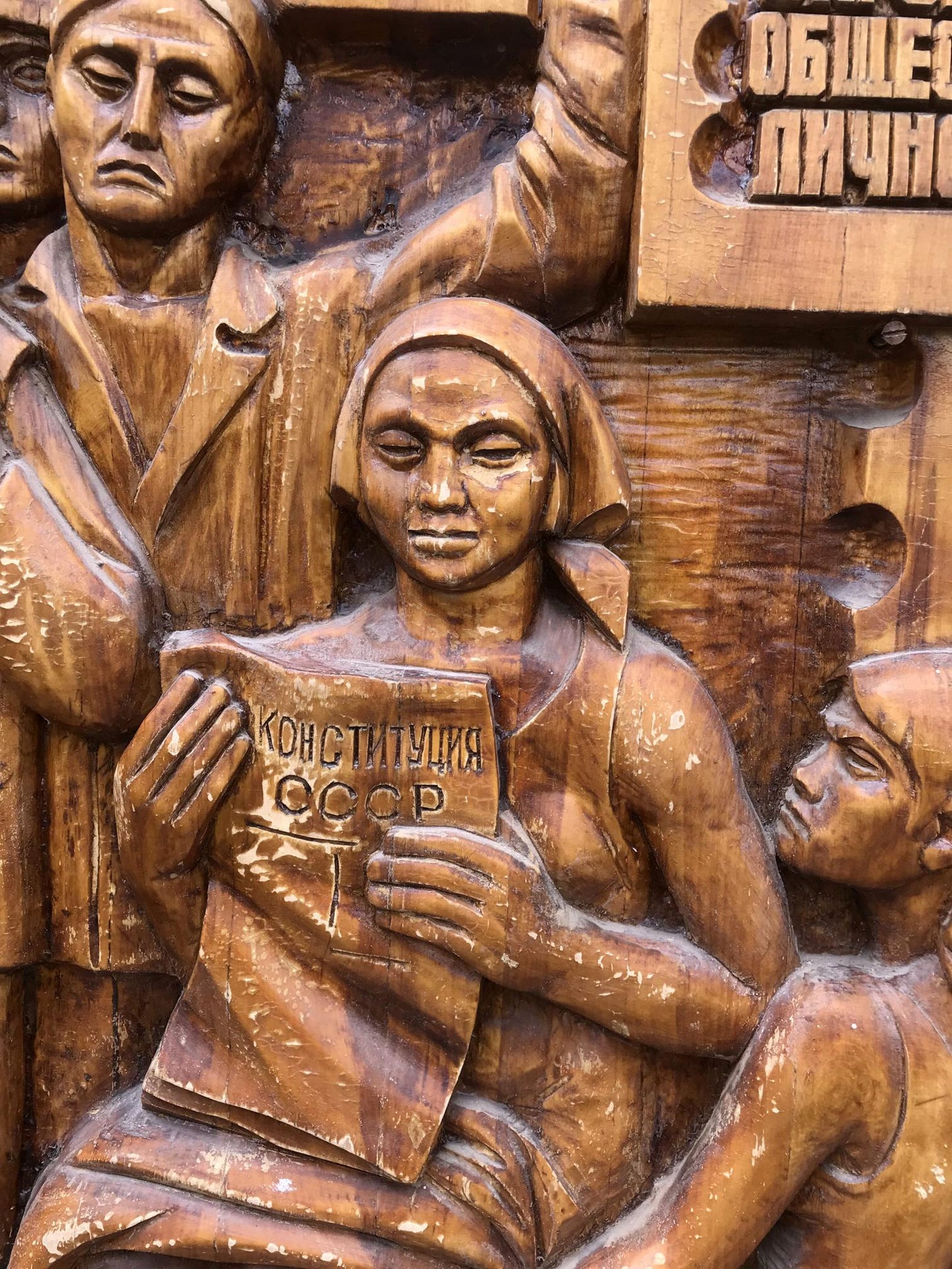 Detailed wooden relief of woman holding USSR Constitution, social realism style
