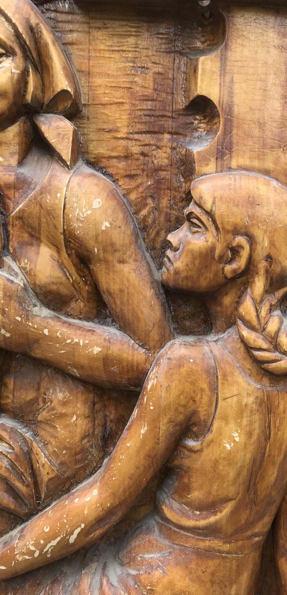 Social realism wooden carving of two figures with braided hair and intricate expressions