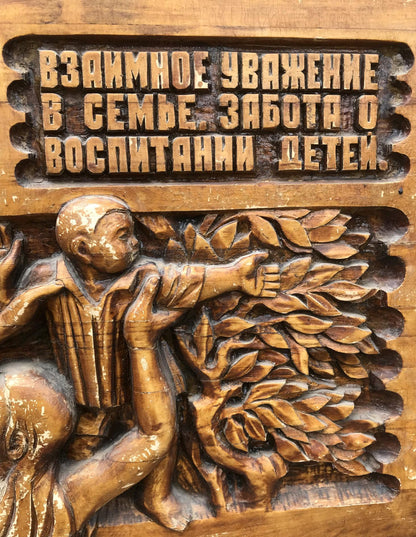 Detailed wooden carving of boy reaching for leaves with R. text, Social realism family respect