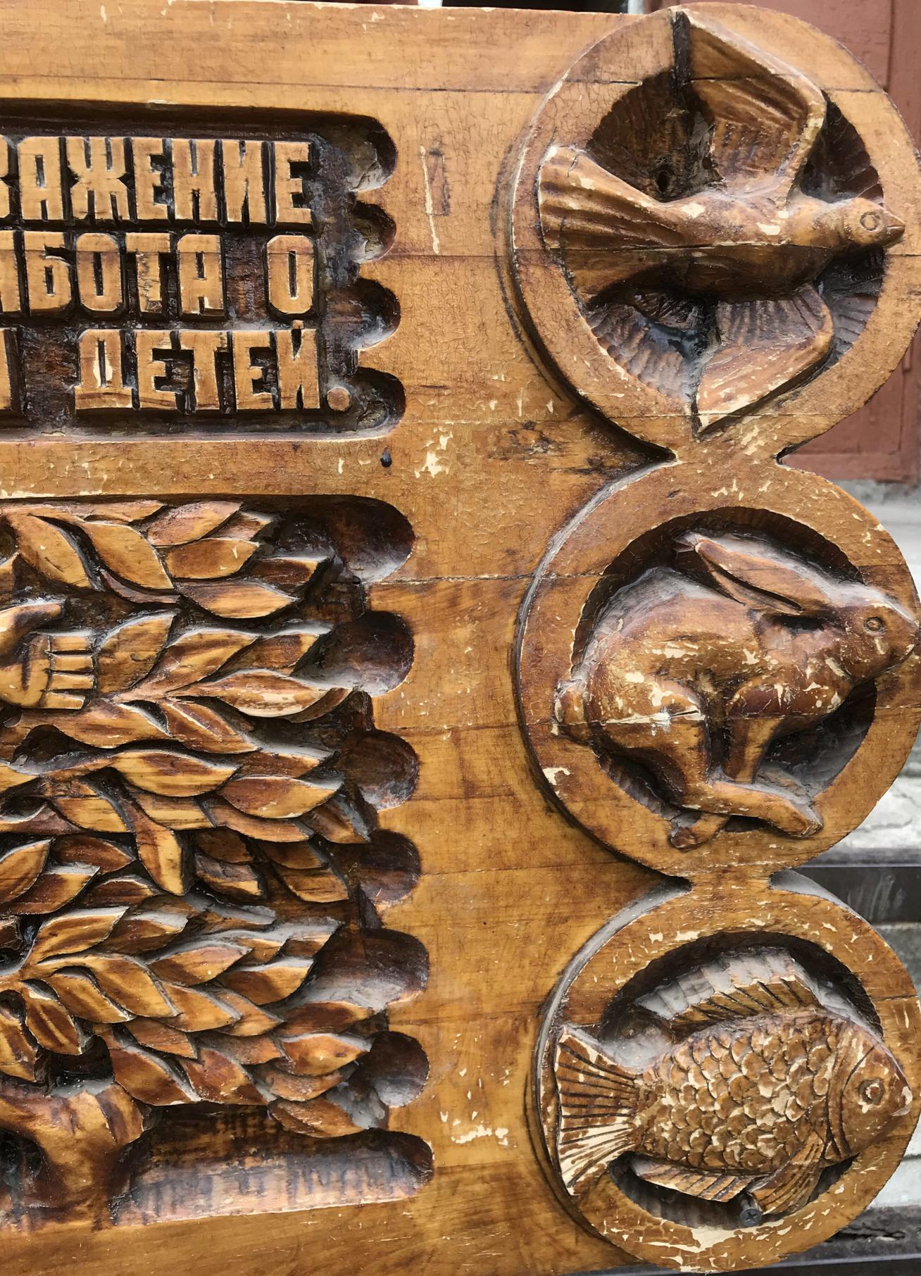 Carved wooden panel with dove, rabbit, fish in circles and wheat, social realism family respect