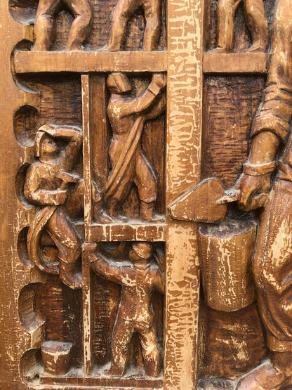 Weathered wooden relief carving of laborious figures in social realism style