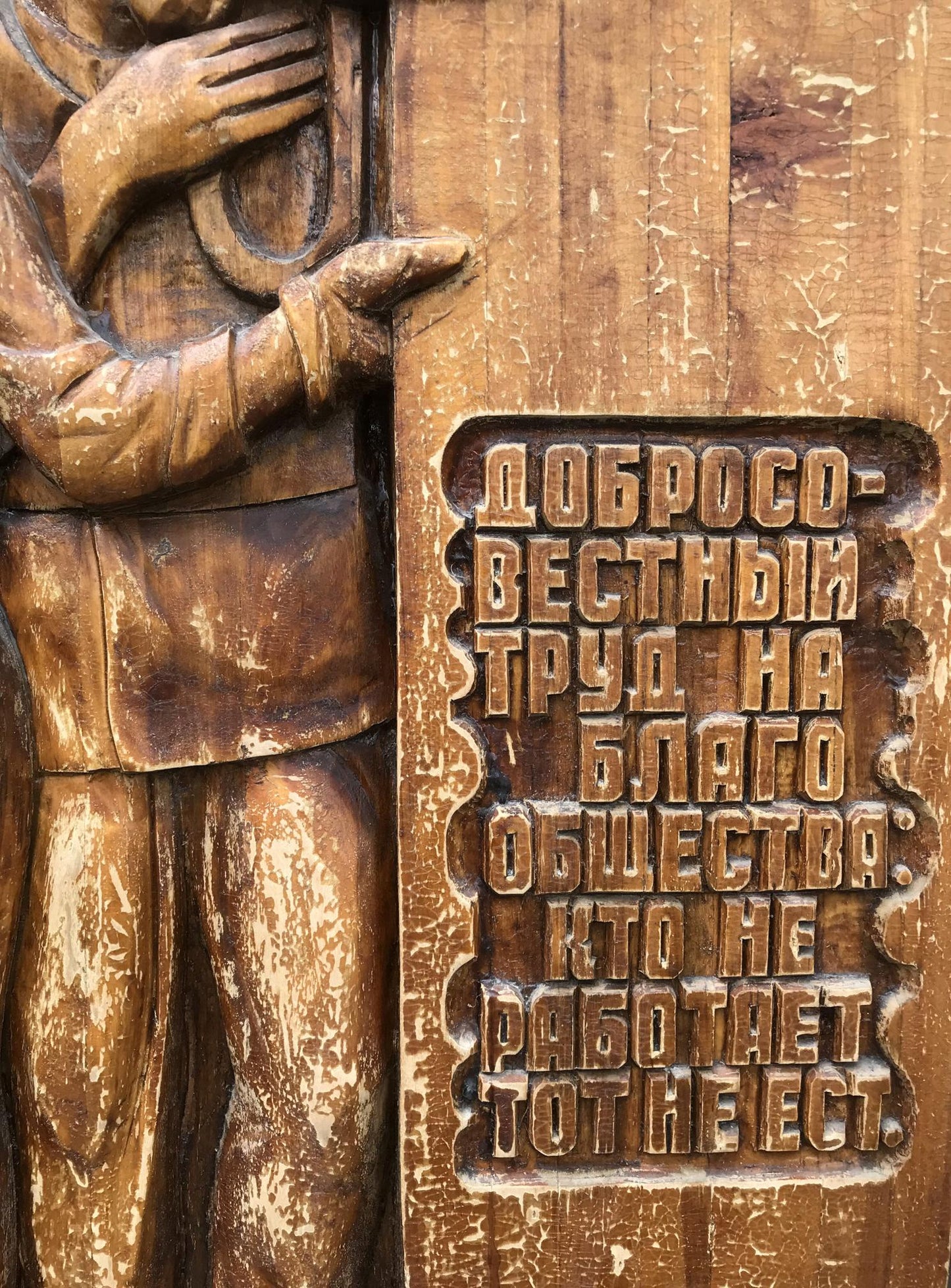Carved wooden plaque of social realism worker with tools and Cyrillic text