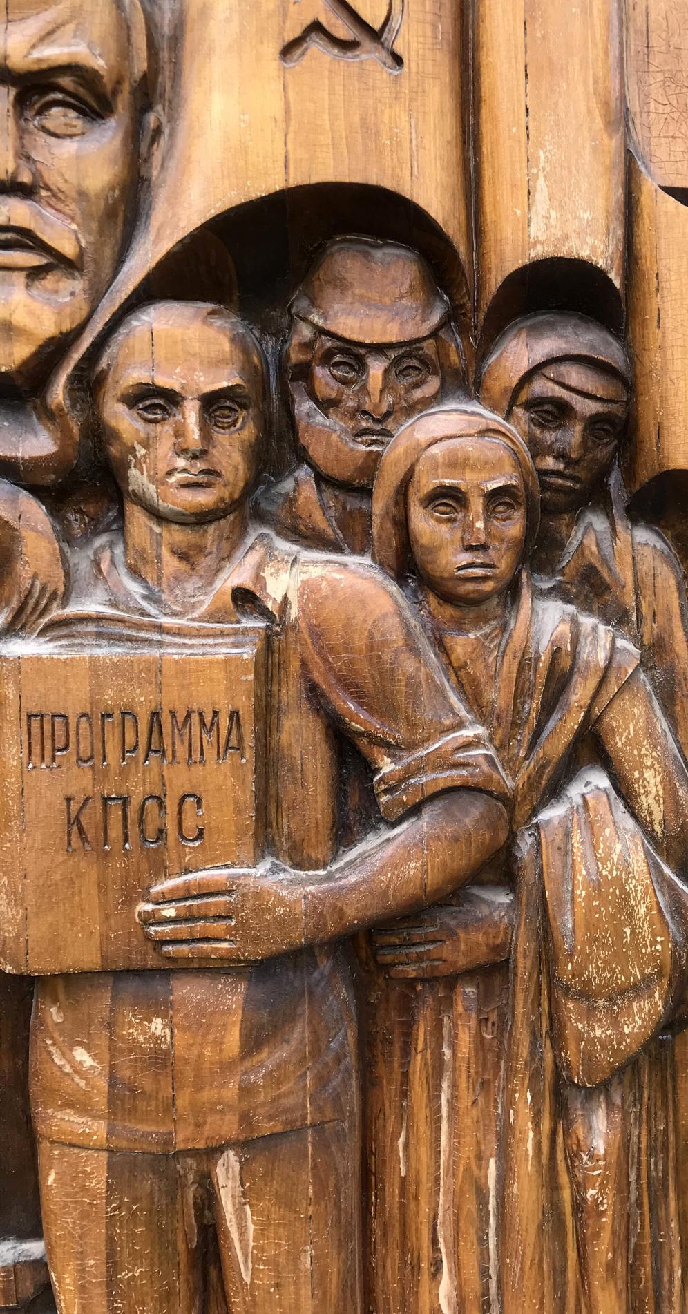 Detailed wooden relief of social realism figures with Cyrillic sign, devotion to communism