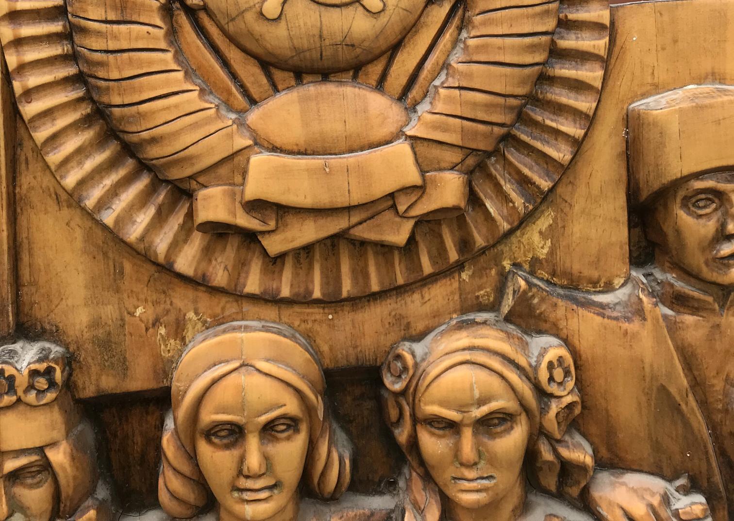 Carved wooden relief of USSR peoples friendship faces under emblem