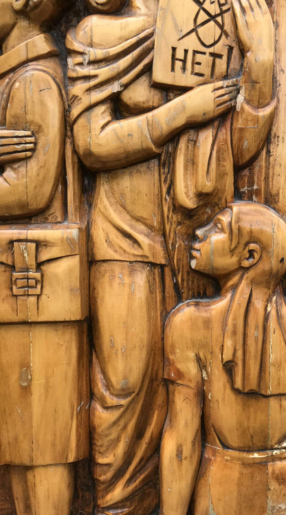 Detailed wooden relief carving of fraternal solidarity figures holding HETI sign