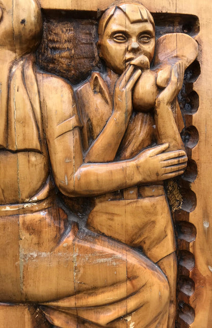 Detailed wooden carving of seated breastfeeding mother in social realism style
