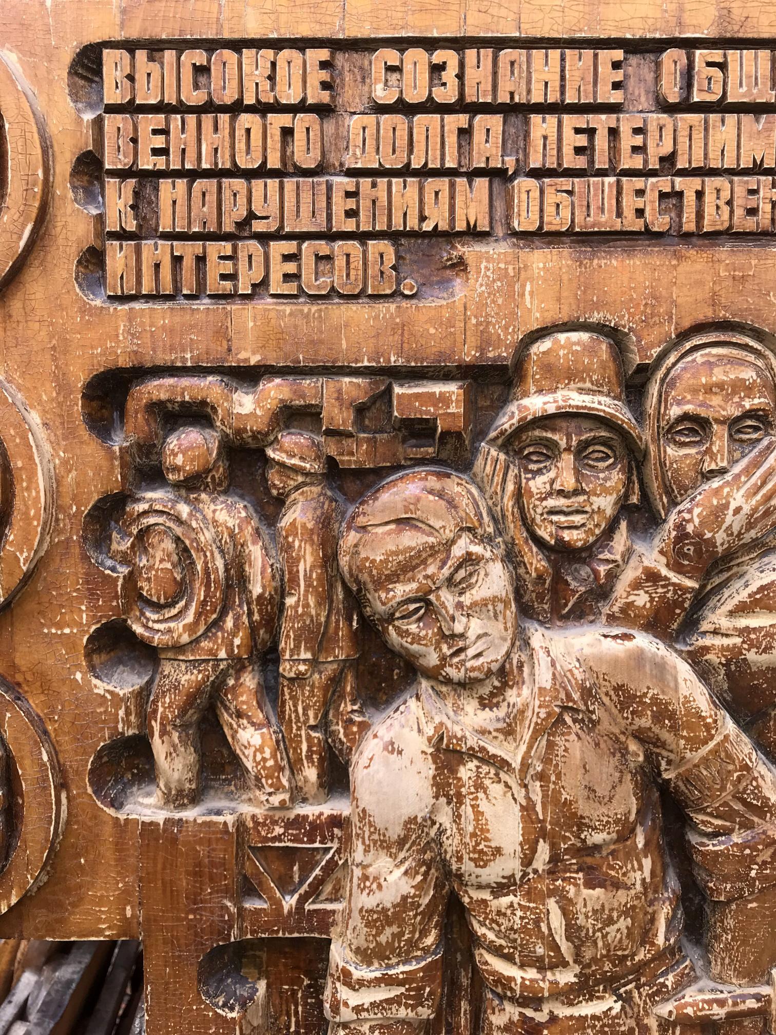 Carved wooden relief panel with Cyrillic text and social realism figures