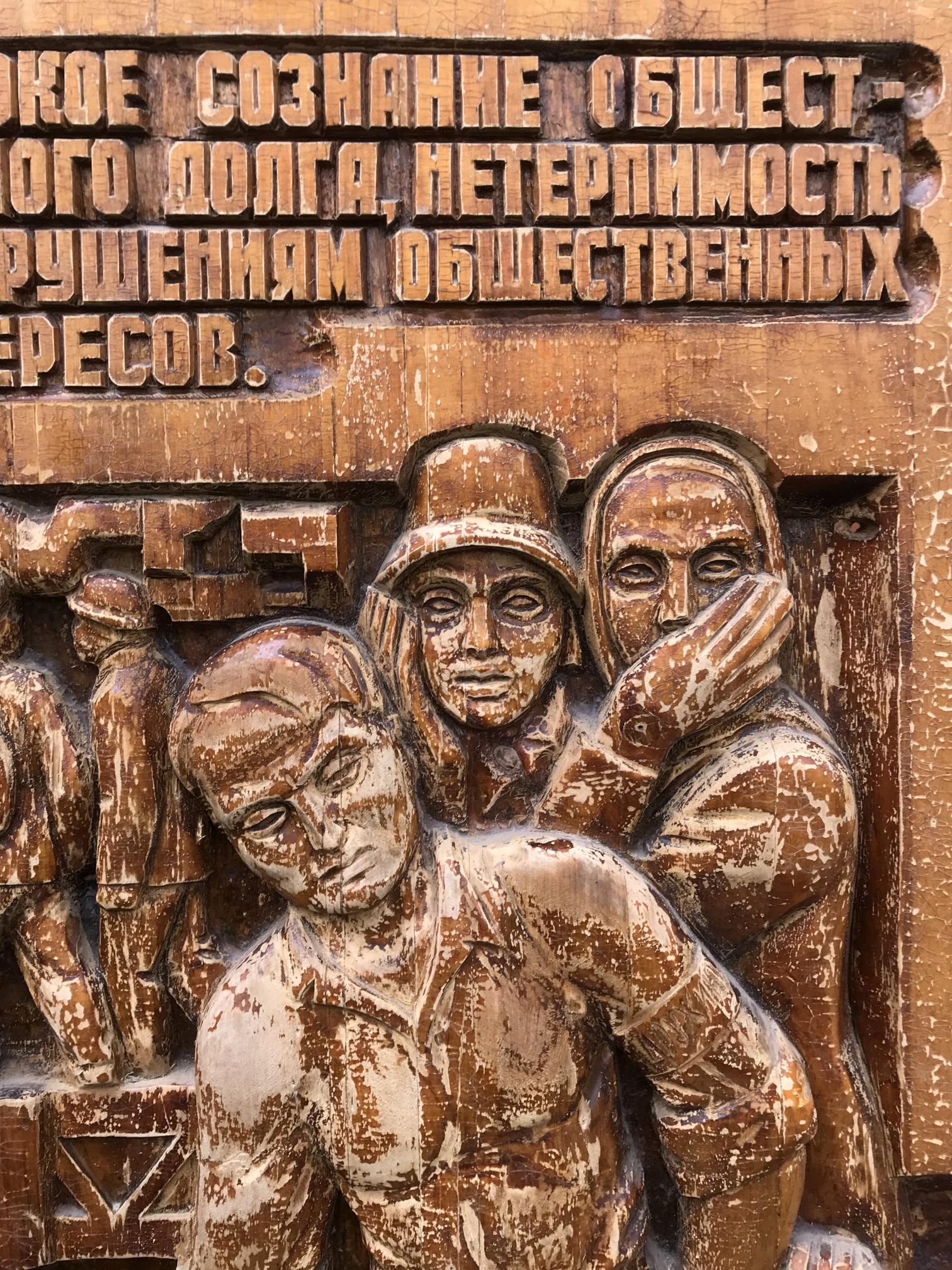 Weathered wooden relief of three expressive figures in social realism style