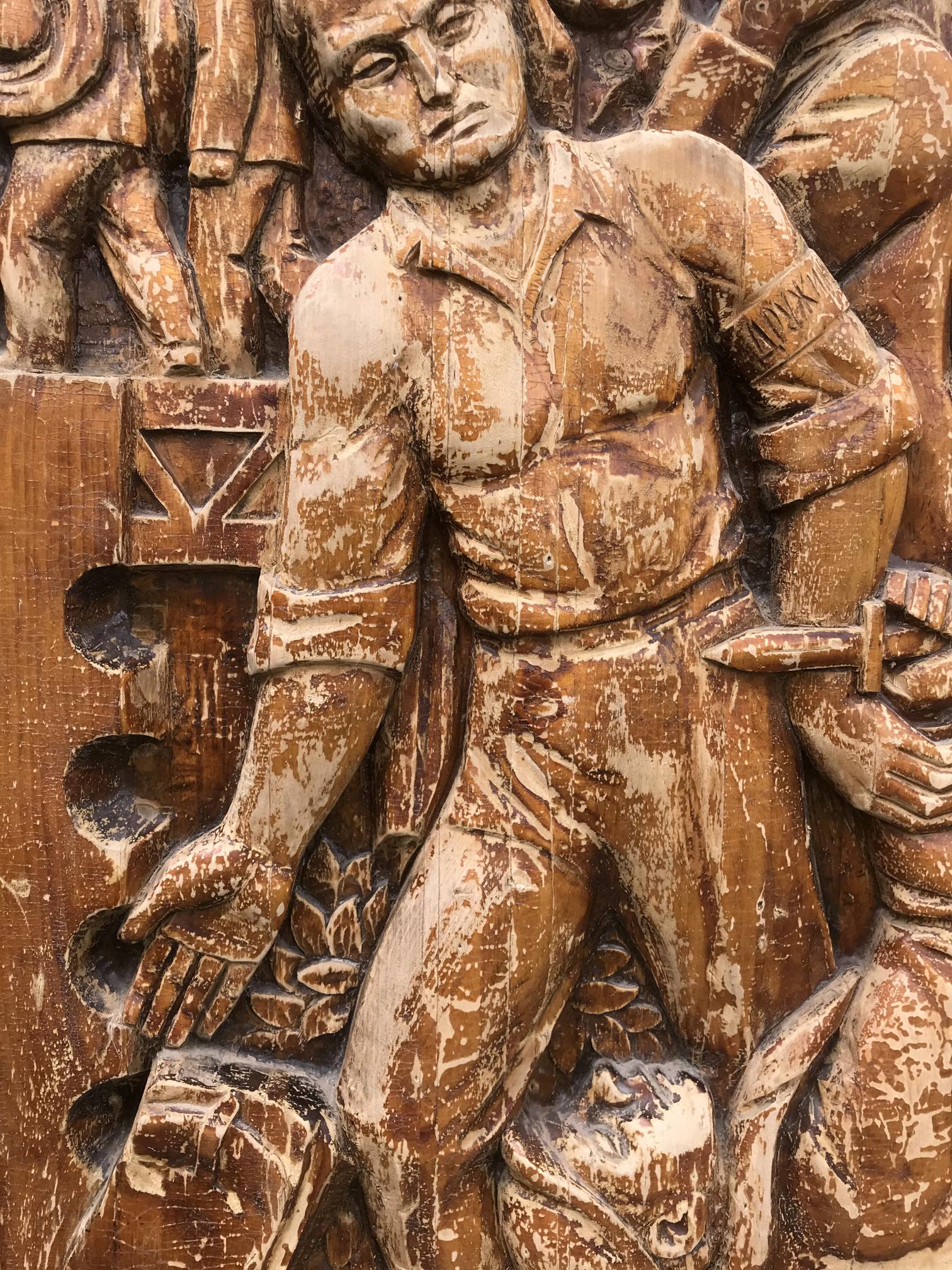 Weathered wooden relief of muscular man in historical attire holding dagger, embodying social realism public duty