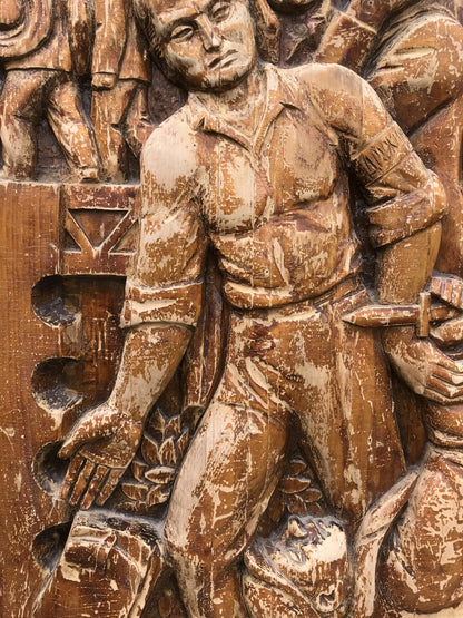 Weathered wooden relief of muscular man in historical attire holding dagger, embodying social realism public duty