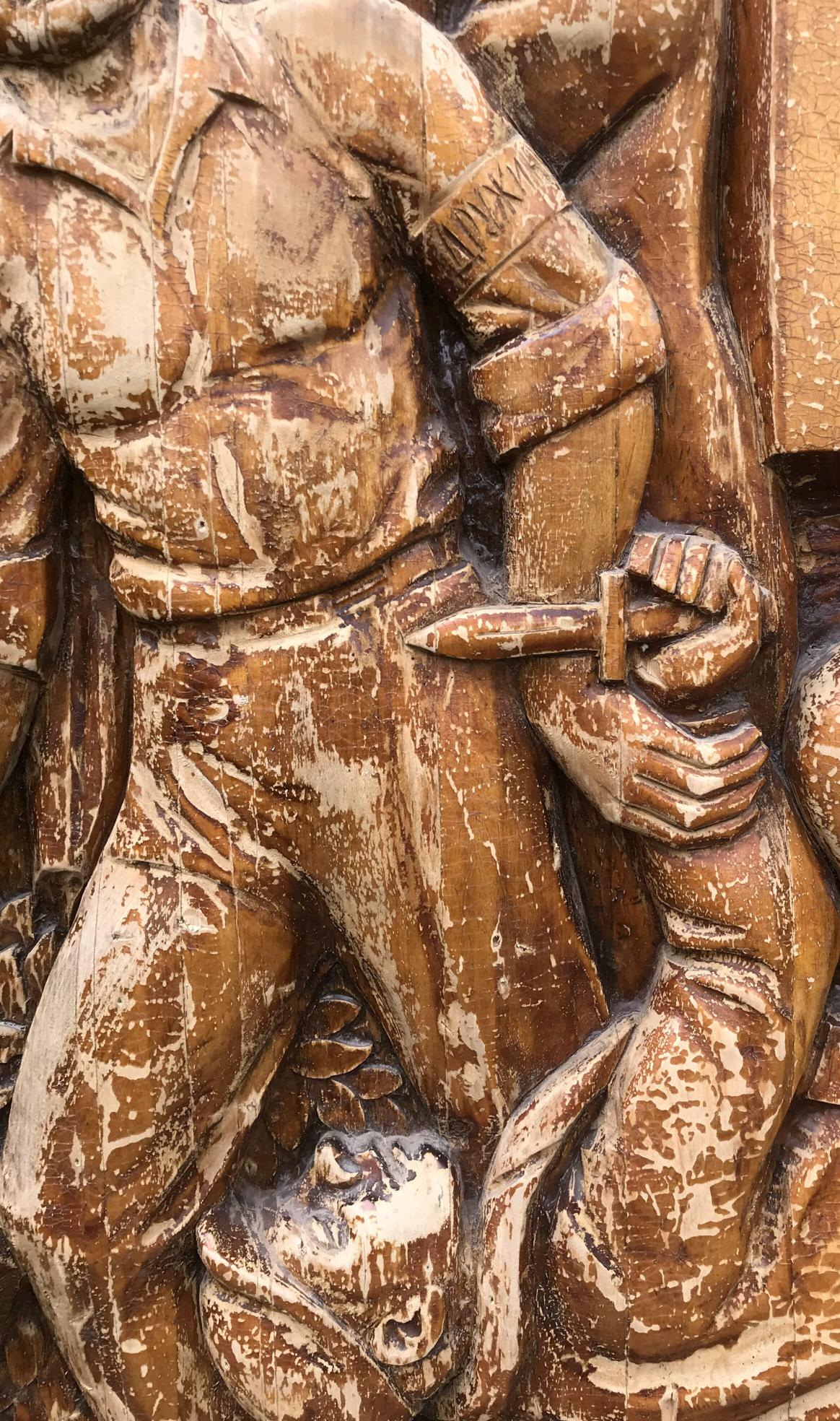 Weathered brown stone relief of muscular warrior in armor holding dagger, social realism style