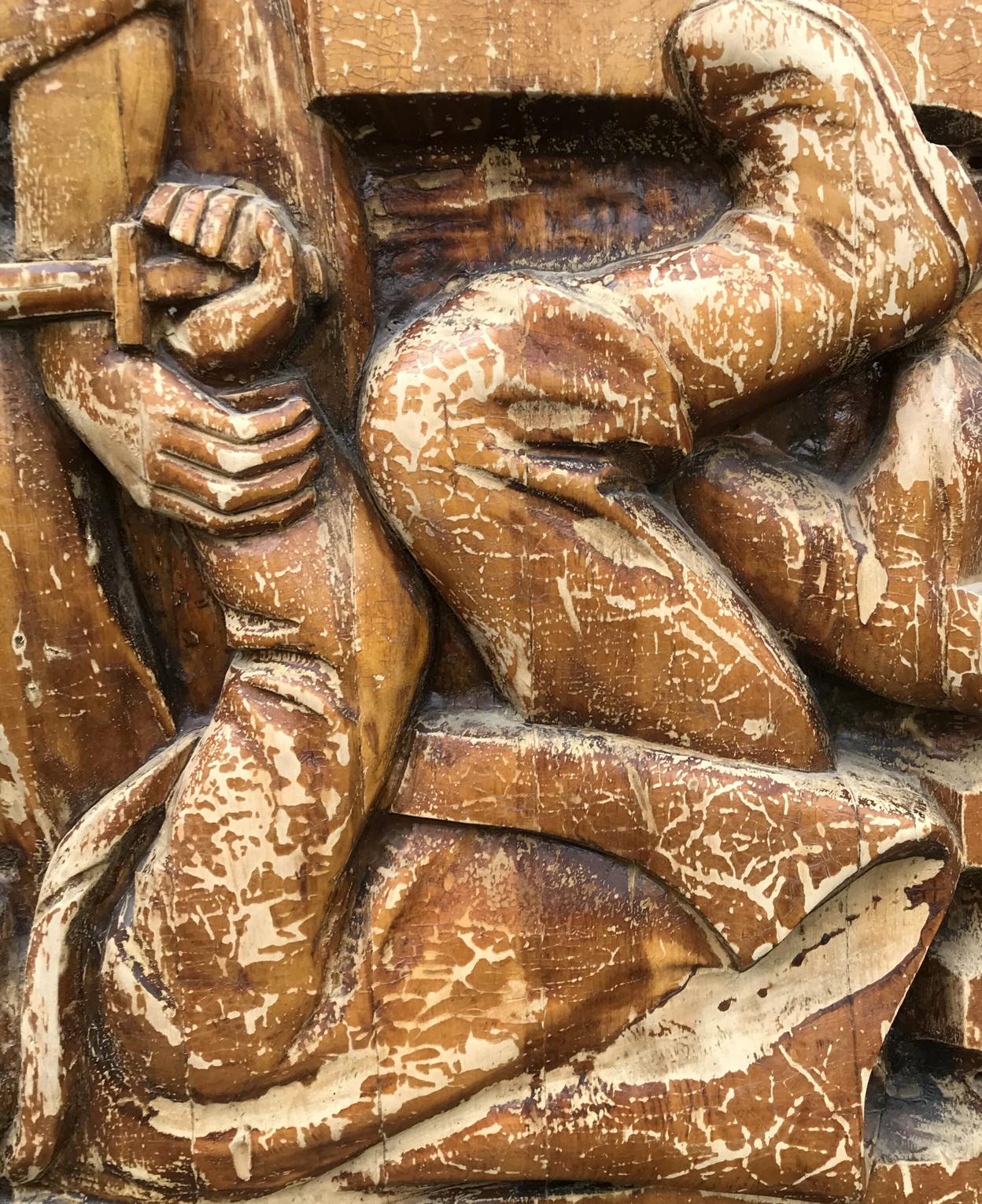 Weathered brown wooden relief of dynamic social realism figure with detailed hands and legs