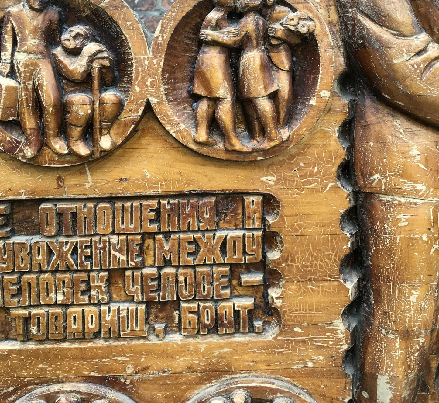 Weathered wooden plaque with social realism carvings and R. text