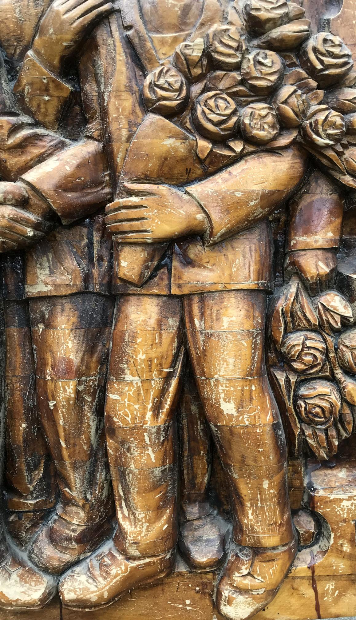 Carved wooden relief of embracing figures in formal attire holding roses, social realism art