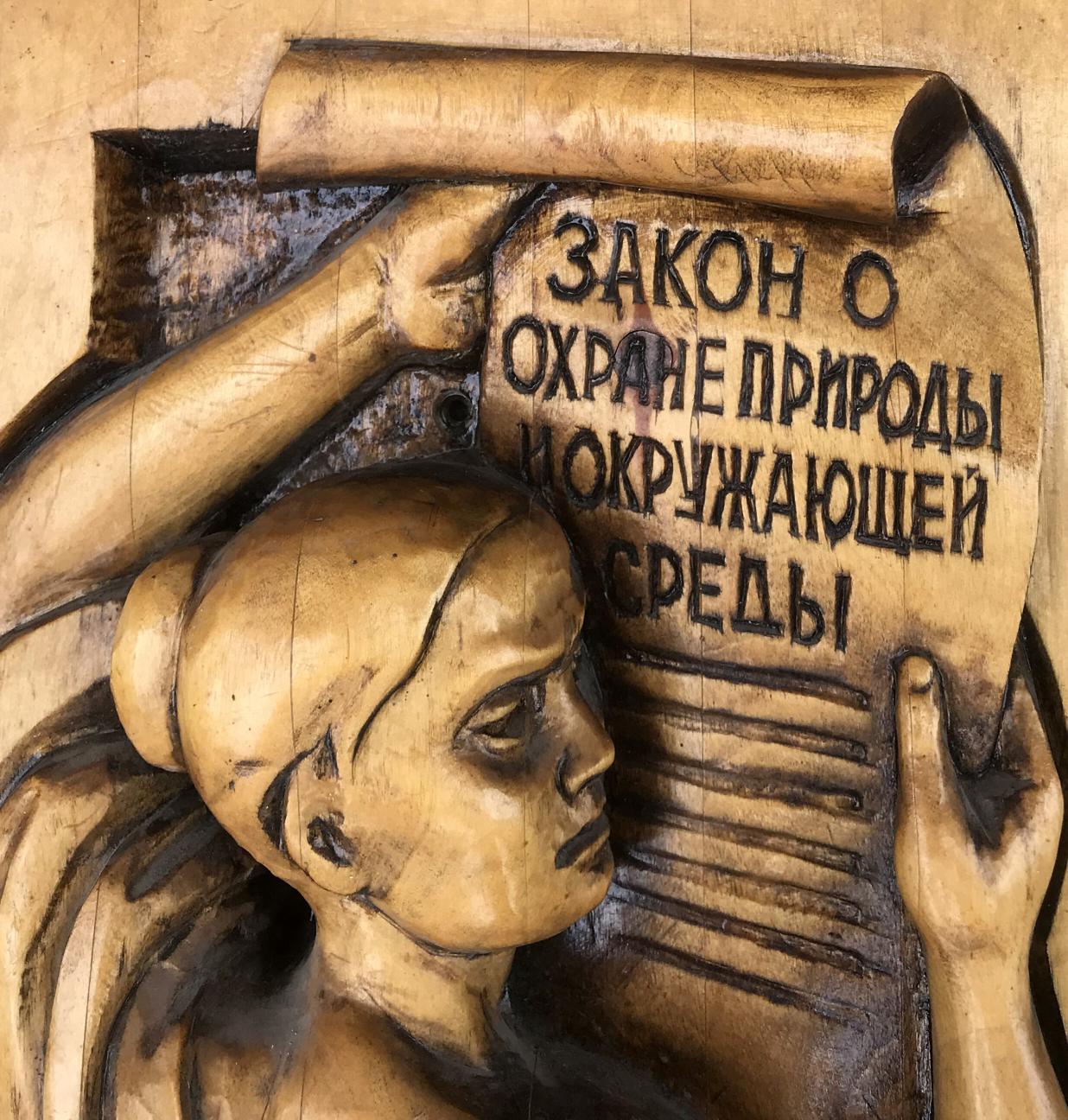 Carved wooden relief of woman holding scroll with R. Law on Nature Protection text