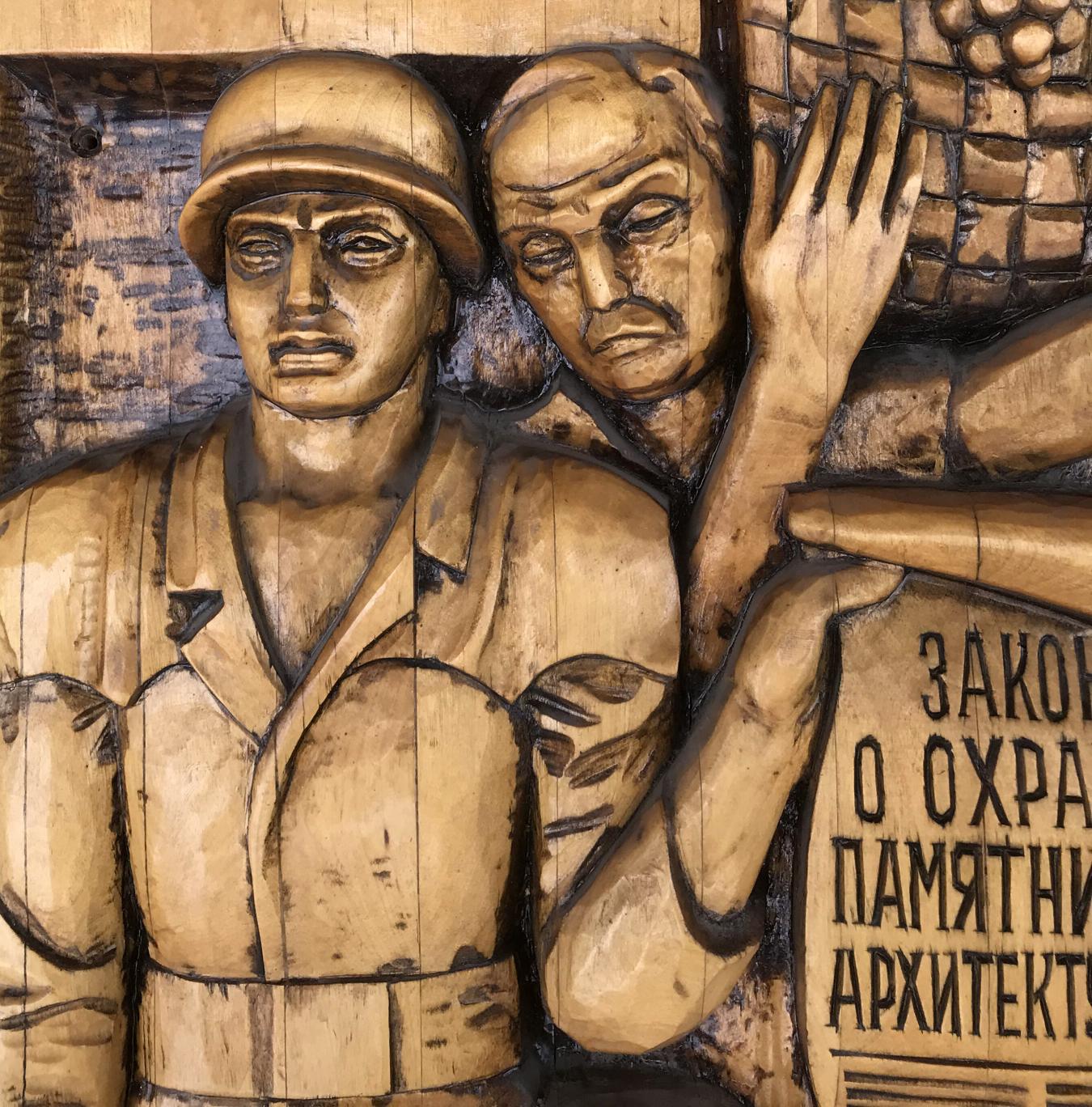 Detailed wooden relief of two soldiers from Social realism Law on Architectural Monuments