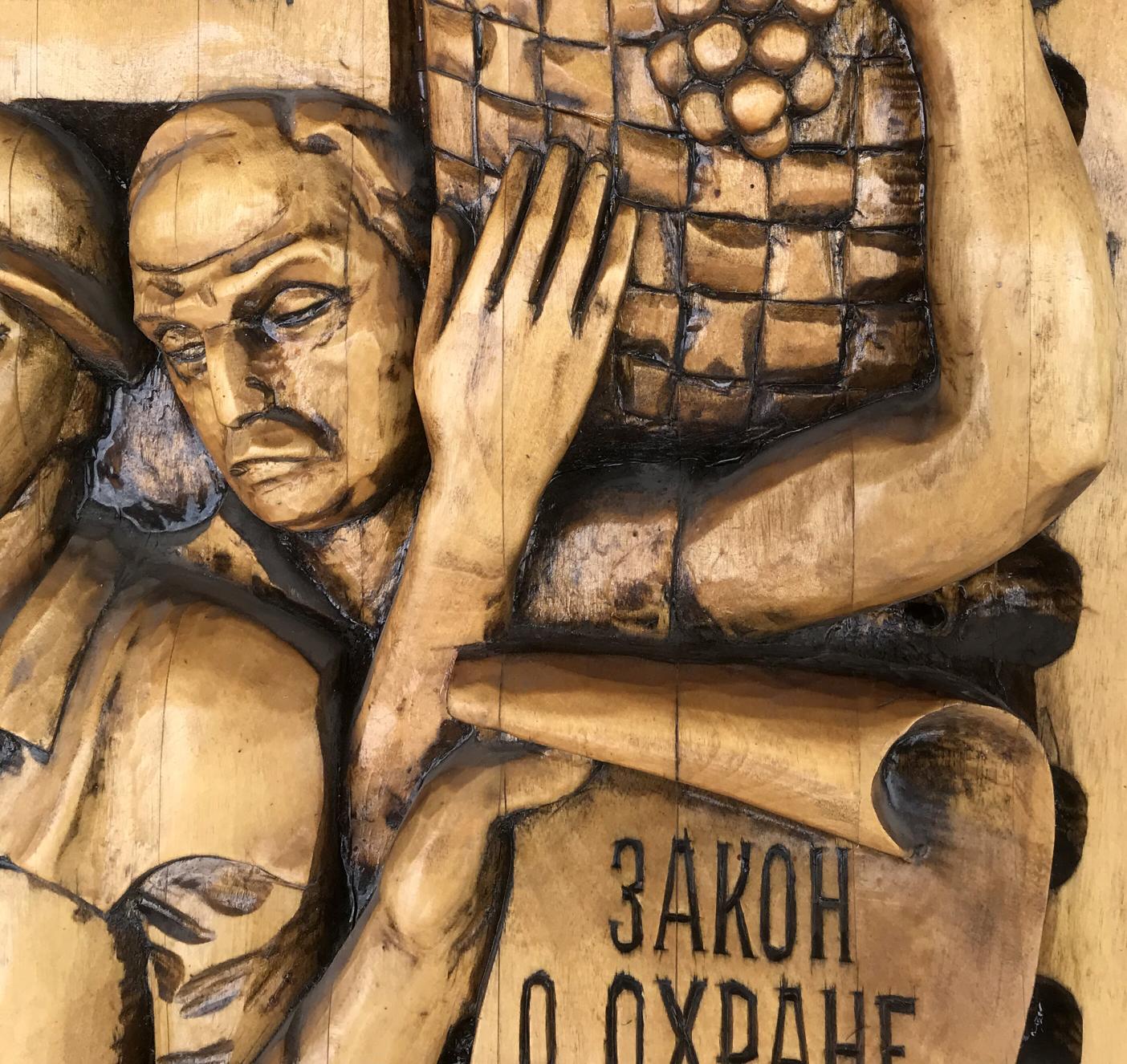 Carved wooden relief man holding grapes, Social realism Law on Architectural Monuments