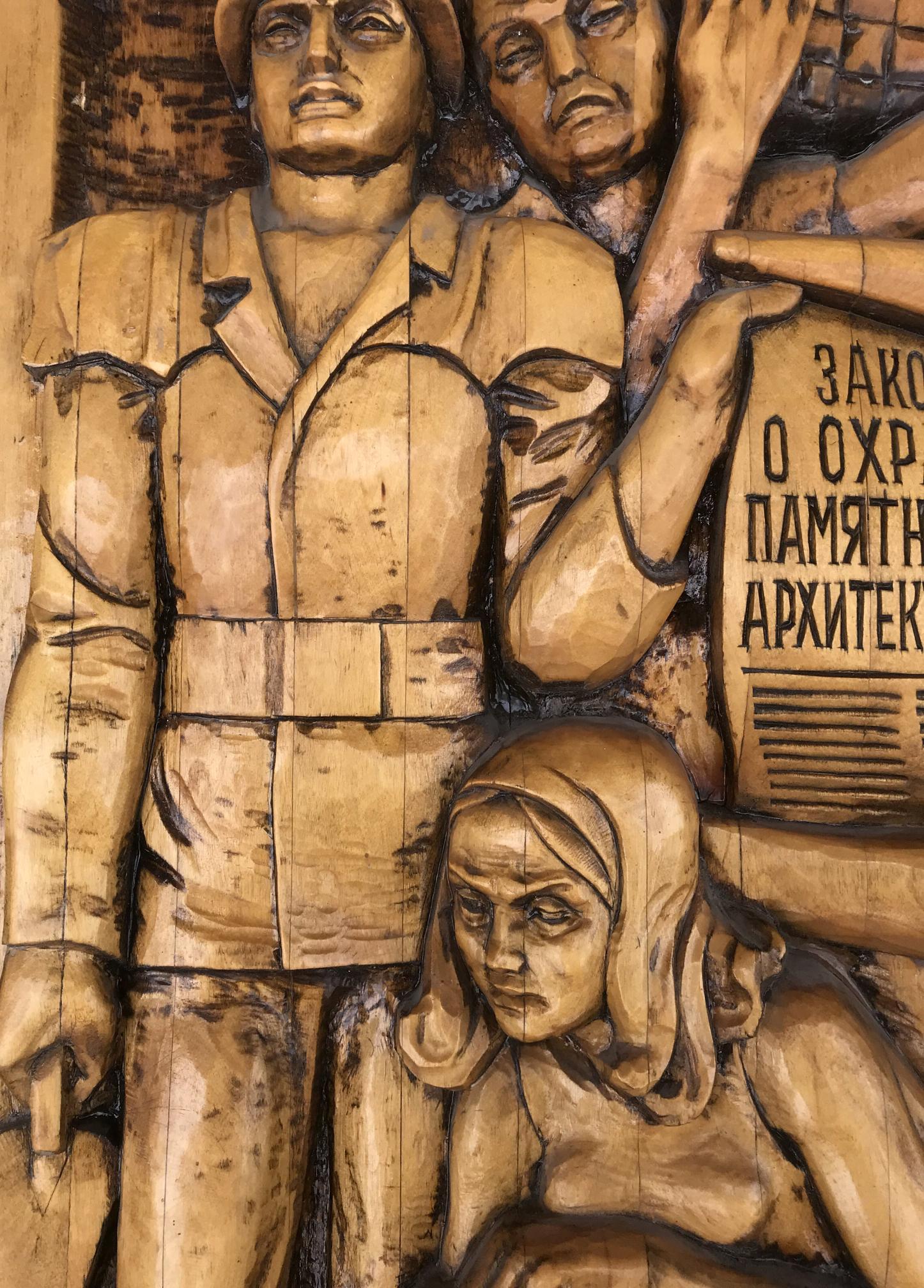 Detailed wooden relief of three somber figures in Social realism Law on the Protection of Architectural Monuments