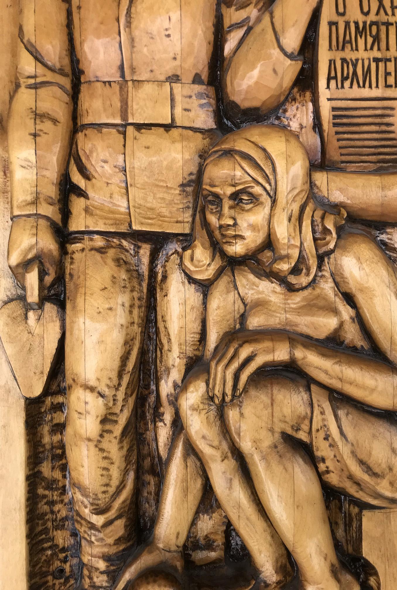 Wood-carved relief of hooded woman by Social realism law figure with tools
