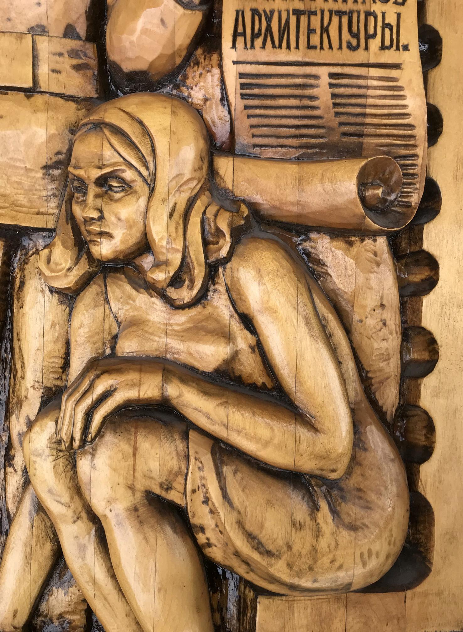 Detailed wooden carving of seated woman in Social realism architectural style