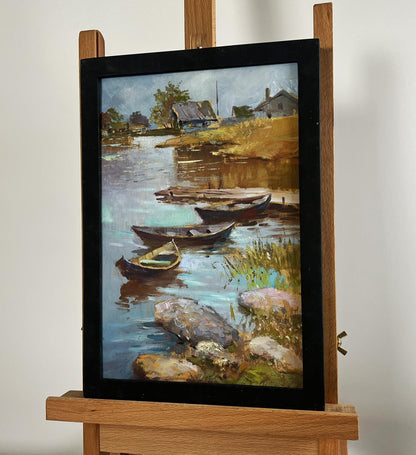 Framed oil painting of serene riverside village boat port by Yuriy Suprunchuk