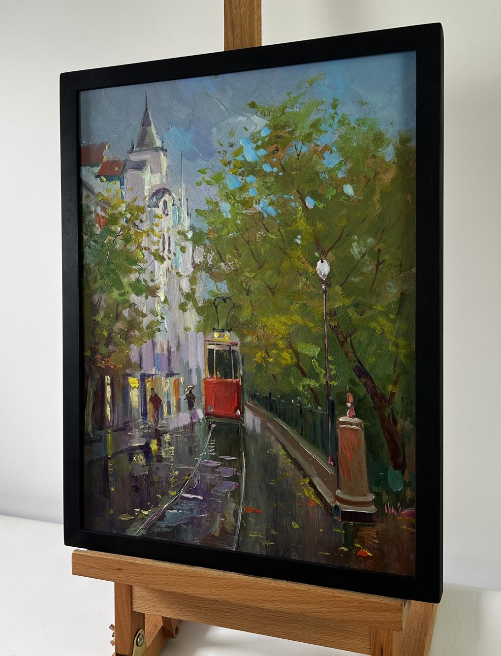 Black-framed oil painting of red tram on wet tree-lined street by Yuri Suprunchuk