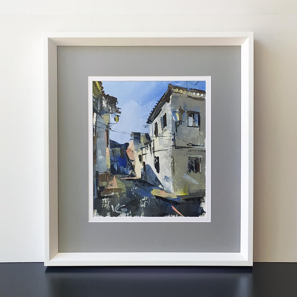 Framed oil painting by Volodymyr Gluhomanyuk of narrow street with white buildings