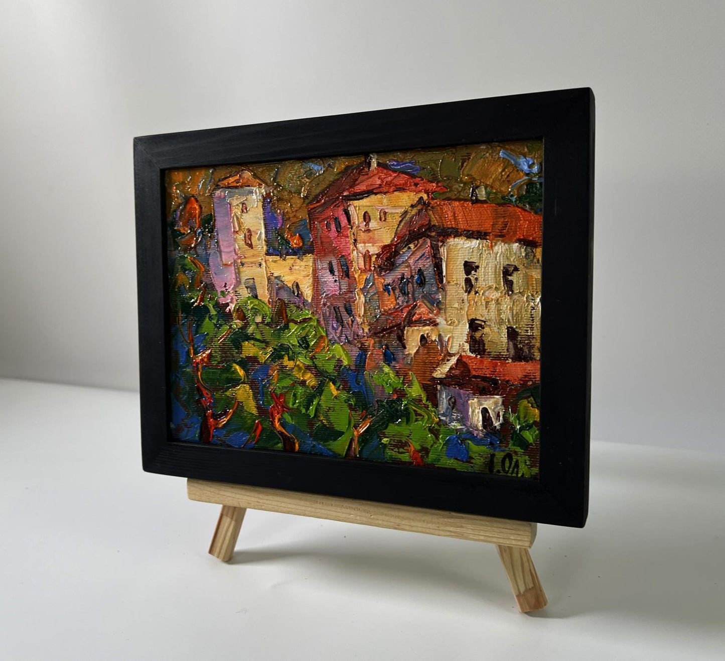 Oil painting Evening city bustle by Oleksiy Ivanyuk in black frame on easel