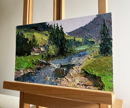 Oil painting of houses in mountains by Boris Serdyuk with green hills and stream