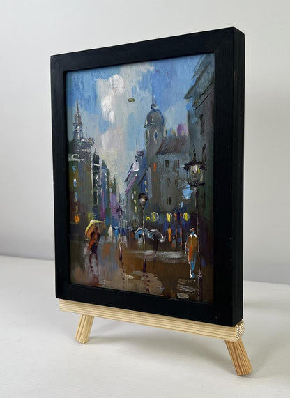 Black-framed oil painting of rainy city street by Yuriy Suprunchuk