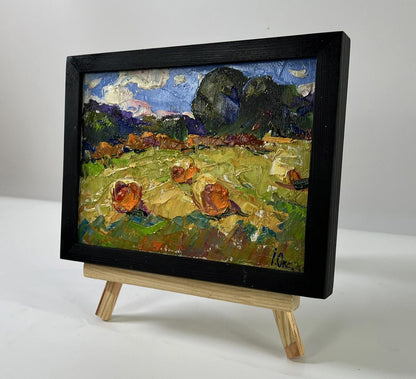 Oil painting Haystacks in field with orange pumpkins by Oksana Ivanyuk on easel