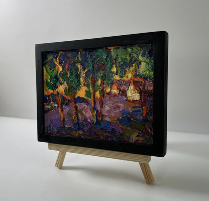 Oil painting of orange sunset behind trees by Oksana Ivanyuk in black frame on easel