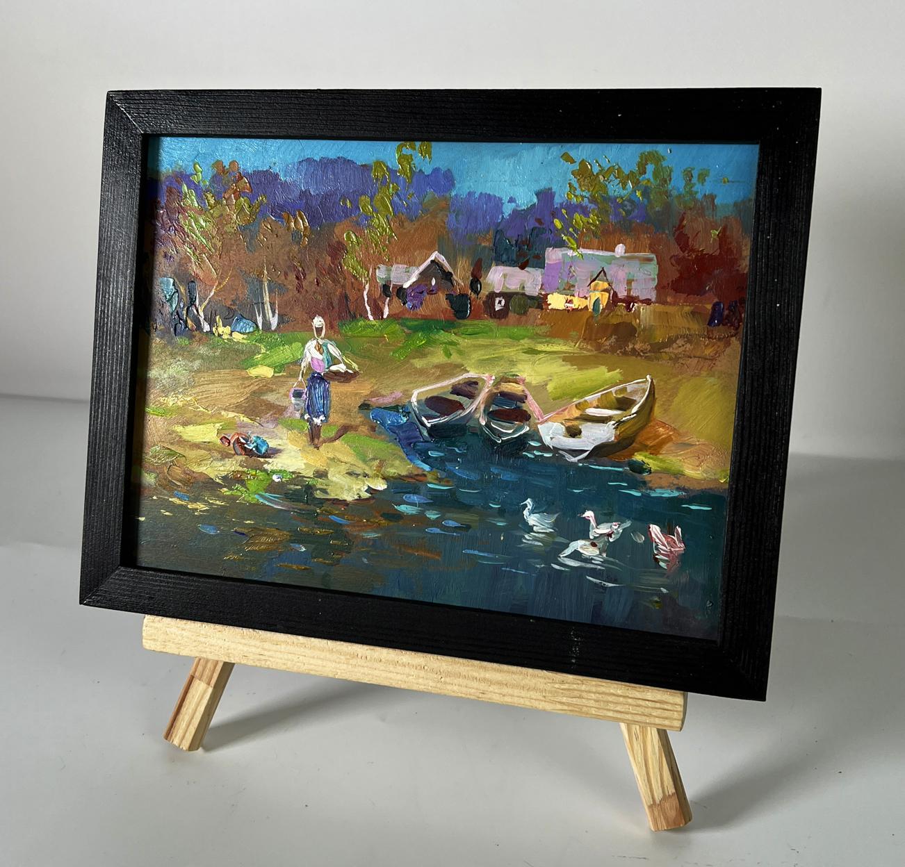 Black-framed oil painting of geese swimming by river by Yuriy Suprunchuk on easel