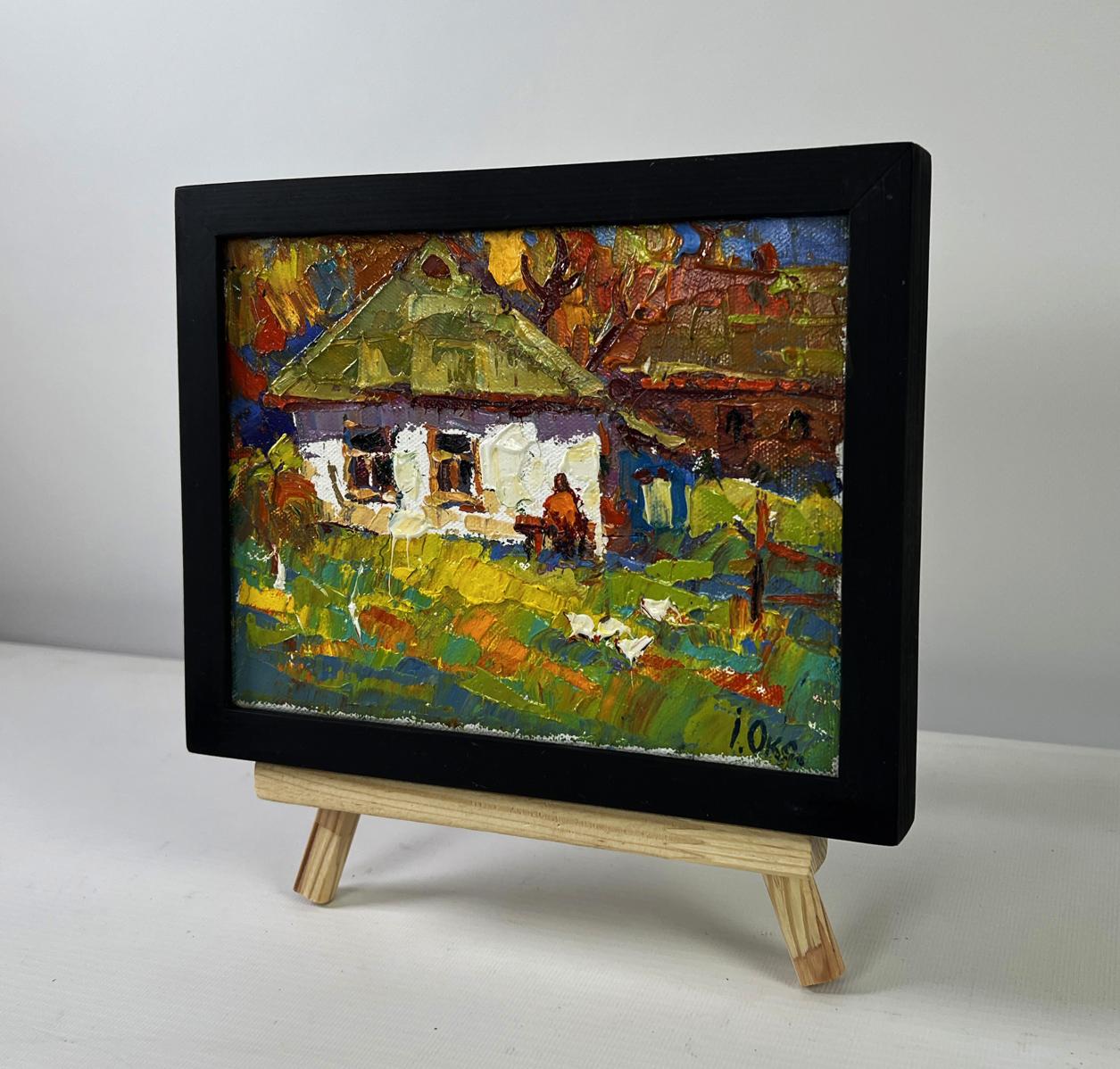 Vibrant impressionist oil painting by Oksana Ivanyuk of rustic autumn house on wooden easel