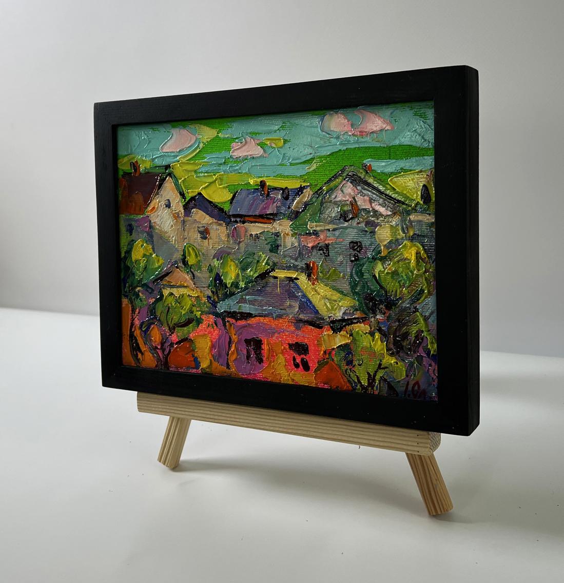 Oil painting of village houses by Oleksiy Ivanyuk in black frame on easel