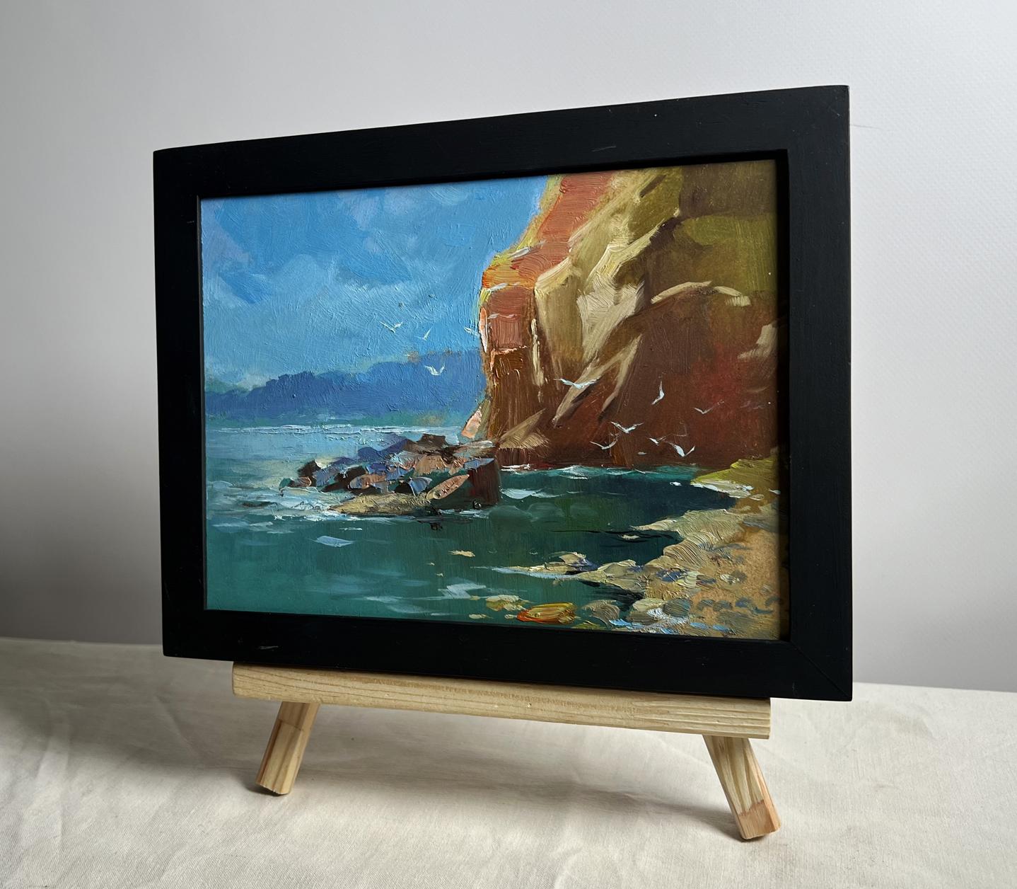 Framed oil painting of Rocky seashore by Yuriy Suprunchuk on wooden easel