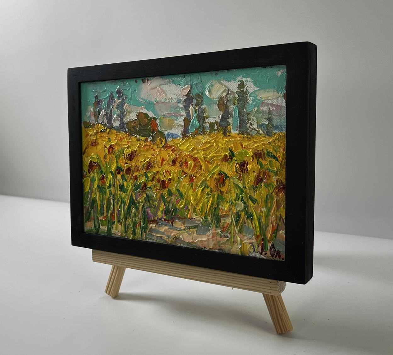 Vibrant oil painting of sunflower field by Oleksiy Ivanyuk in black frame on easel