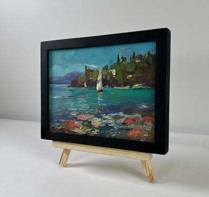 Oil painting of sailboat at sea by Yuriy Suprunchuk in black frame on easel