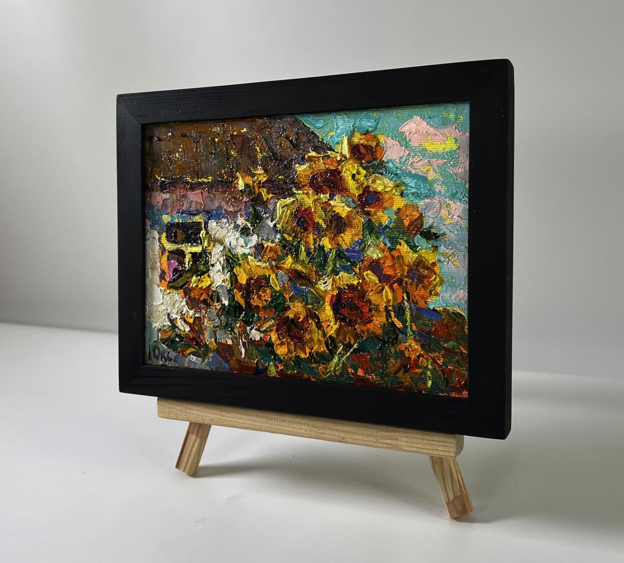 Vibrant oil painting of sunflowers in black frame by Oksana Ivanyuk on easel
