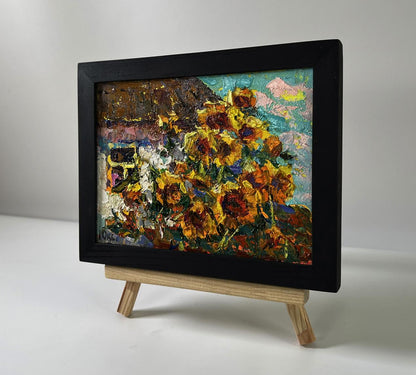 Vibrant oil painting of sunflowers in black frame by Oksana Ivanyuk on easel