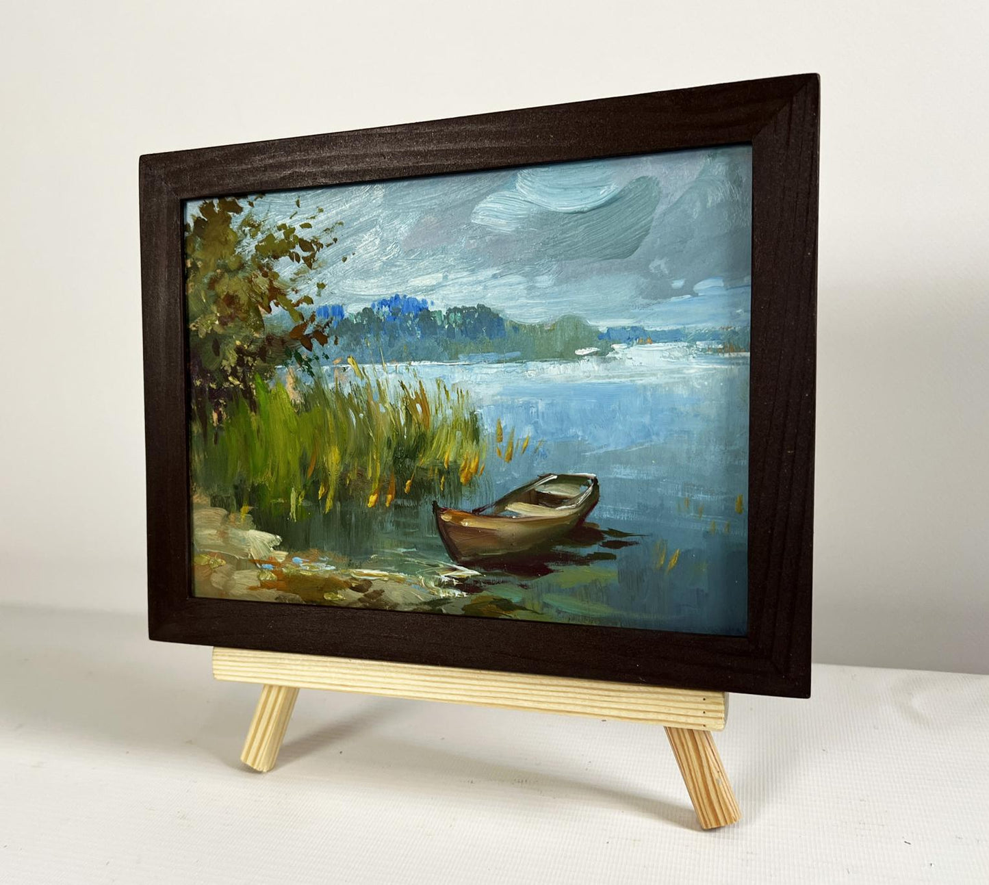 Oil painting of boat among reeds by Yuriy Suprunchuk in wood frame
